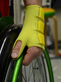 Mit einer Silikon-Handorthese wird ein Rollstuhl angetrieben