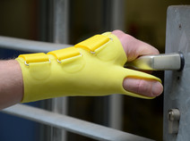 Mit einer Unterarm-Hand-Silikonorthese wird eine Tür geöffnet.